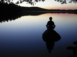 Homme méditant sur un lac à la tombée de la nuit